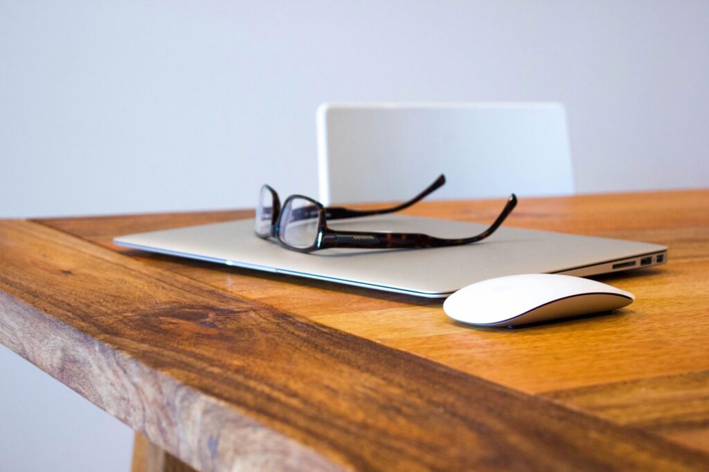 Laptop with pair of glasses on a wooden desk