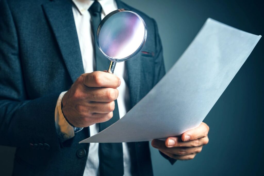 Male hands holding magnifying glass over a piece of paper