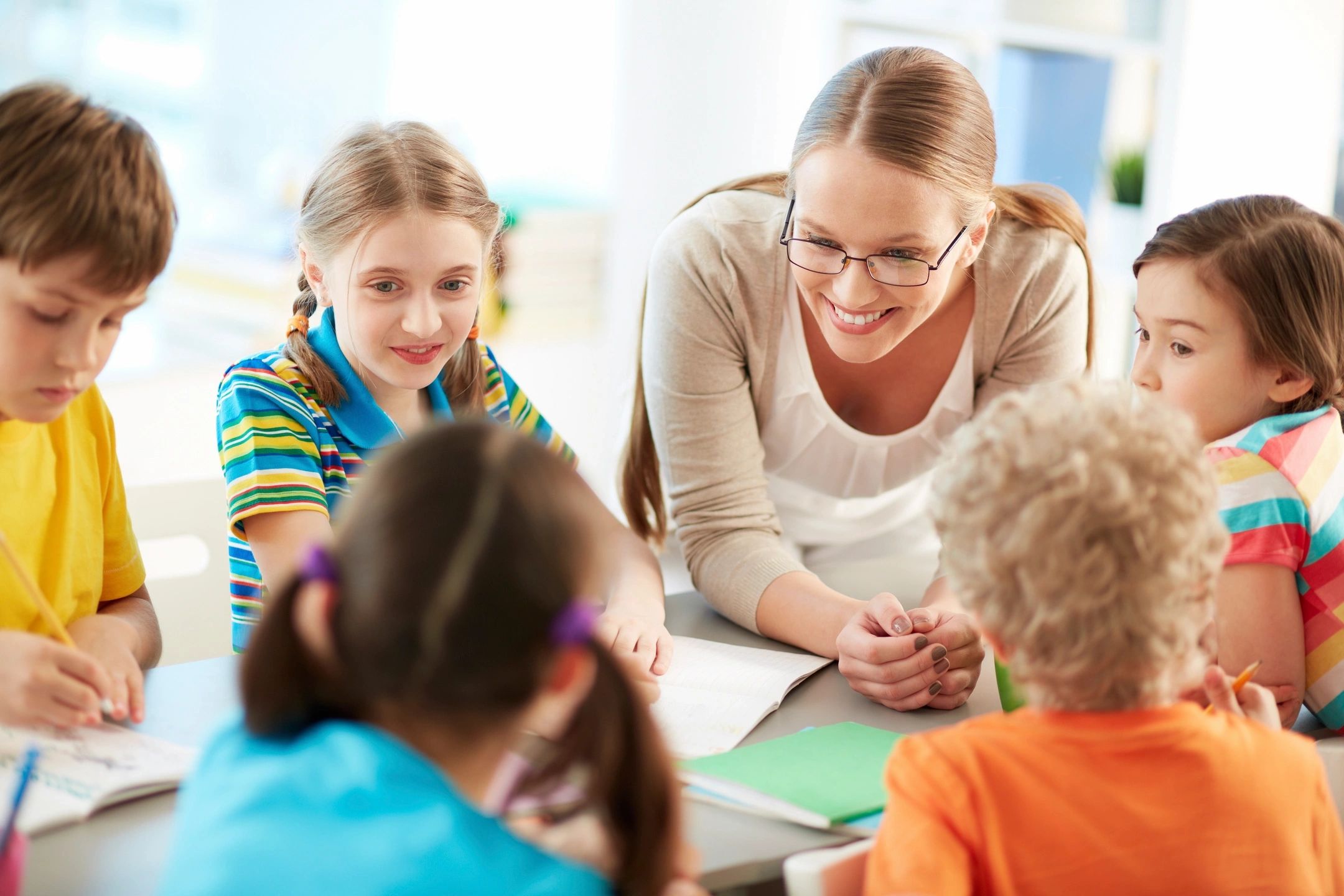 Woman smiling at kids sitting around a table