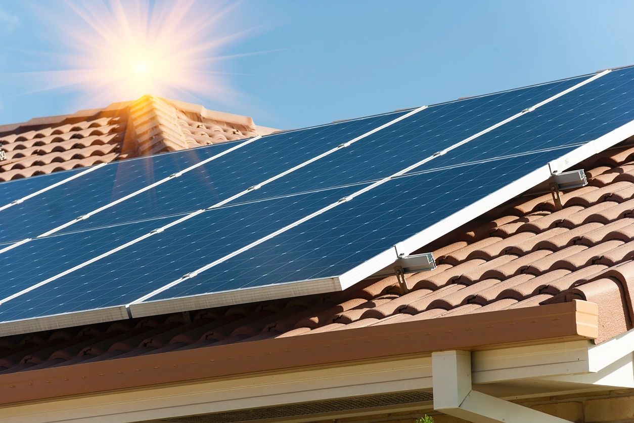 Solar panels on a roof with the sun shining overhead