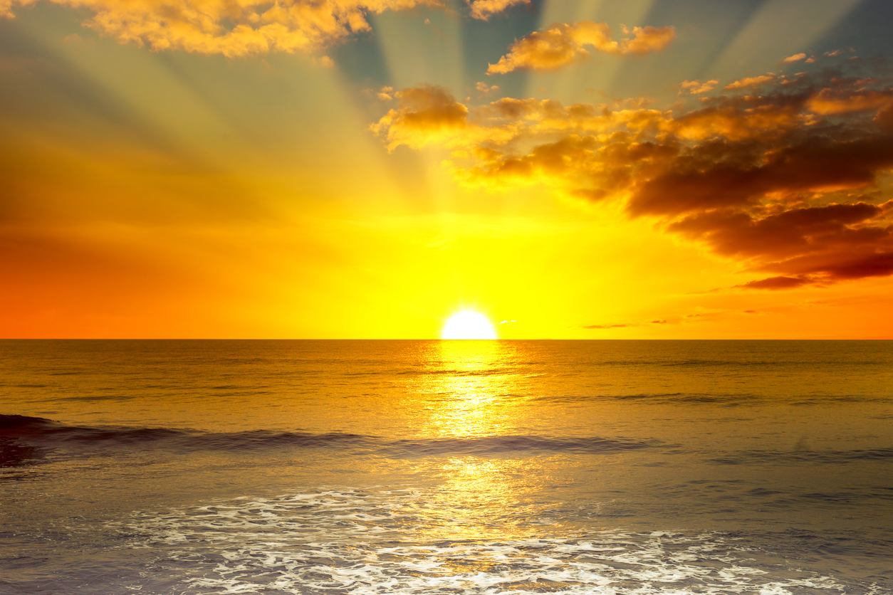 Majestic bright sunrise over ocean and light waves on blue sea.