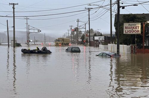A photo of a street completely underwater when only the top 1/4 of cars are visible.