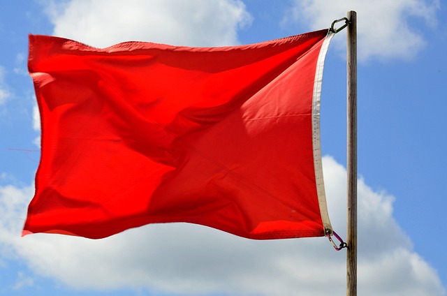 Red flag on a pole blowing on a windy day.