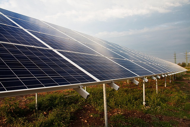 A group of solar panels over a field with the sun overhead.