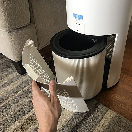 Image of an in-home air purifier for smoke. It looks like a white cylinder with a smaller round accordion filter inside. 