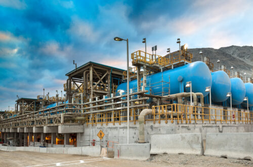 A photo of a desalination plant showing blue water tanks and pipes in an open concrete structure.