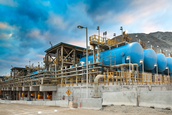 A photo of a desalination plant showing blue water tanks and pipes in an open concrete structure.