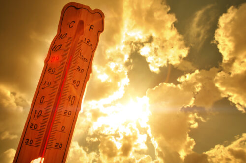 An image of a hot sun surrounded by clouds with a melting, red thermometer