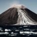 A photo of a volcanic island showing a landslide of rock and ice pouring down the face.