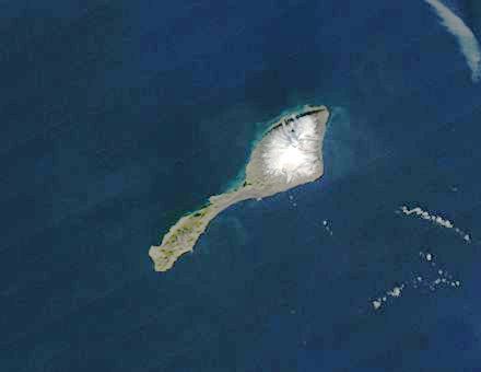 A picture of a tiny island off of Greenland that is shaped like a guppy. The larger side is covered in snow.