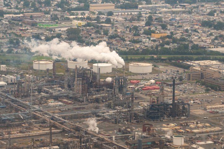 Example of a lack of environmental justice using an image of a power plant billowing smoke in the with houses nearby.