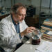 Image of a scientist with his hand on a crystal ball, which is not really how climate models work! He's surrounded by book and pages of data.